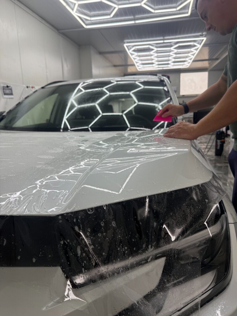 Aplikator układa bezbarwną folię PPF na masce Toyoty RAV4 2026