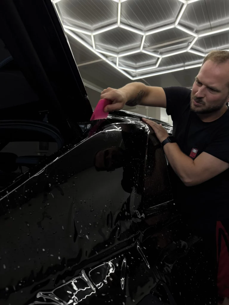 Instalator dopasowuje folię do bocznego elementu nadwozia Audi Q8