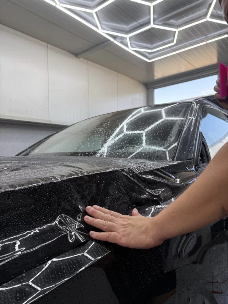 Dopasowywanie dłonią folii do powierzchni maski Audi Q8