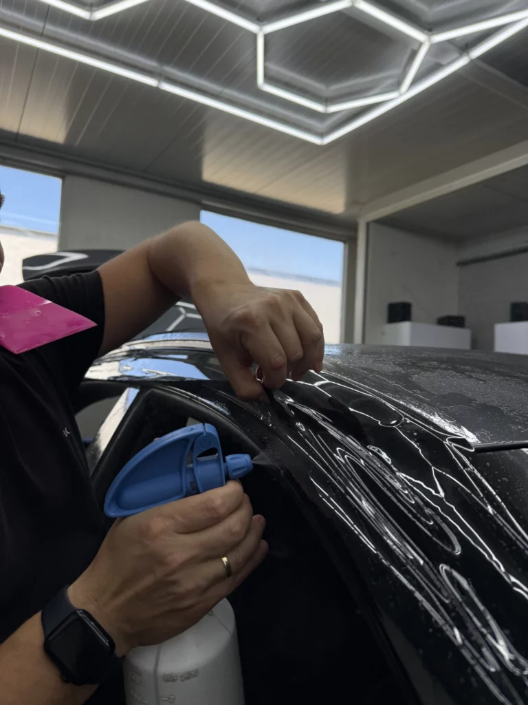 Zbliżenie dłoni instalatora dopasowującego folię przy krawędzi elementu Audi Q8