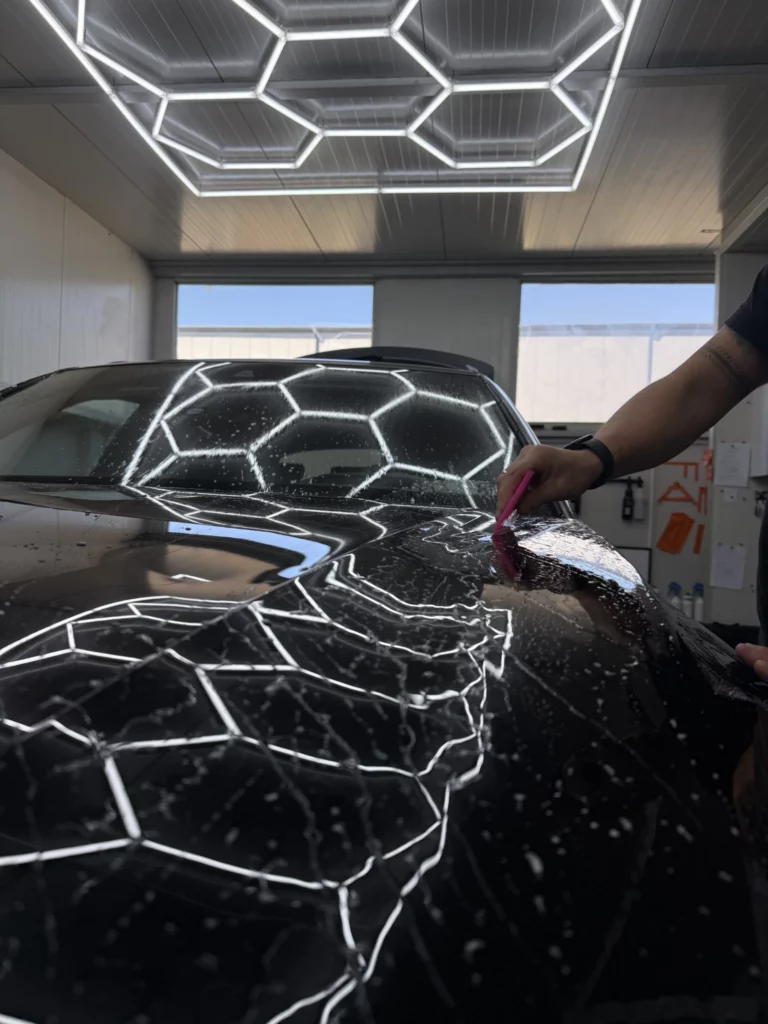 Wygładzanie folii na masce Audi Q8 z odbiciami oświetlenia warsztatu