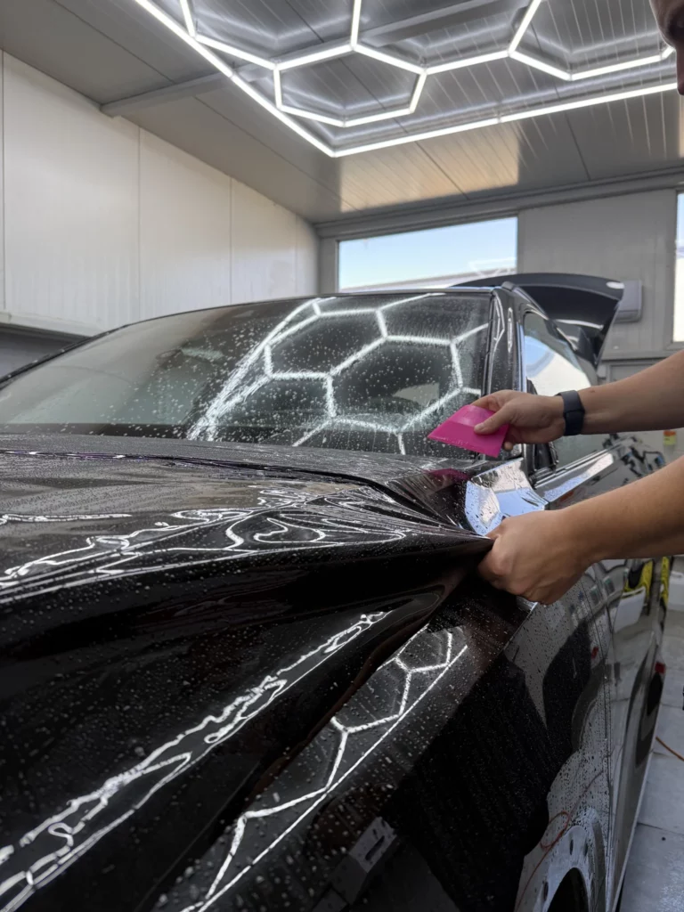 Układanie folii przy bocznej krawędzi maski Audi Q8