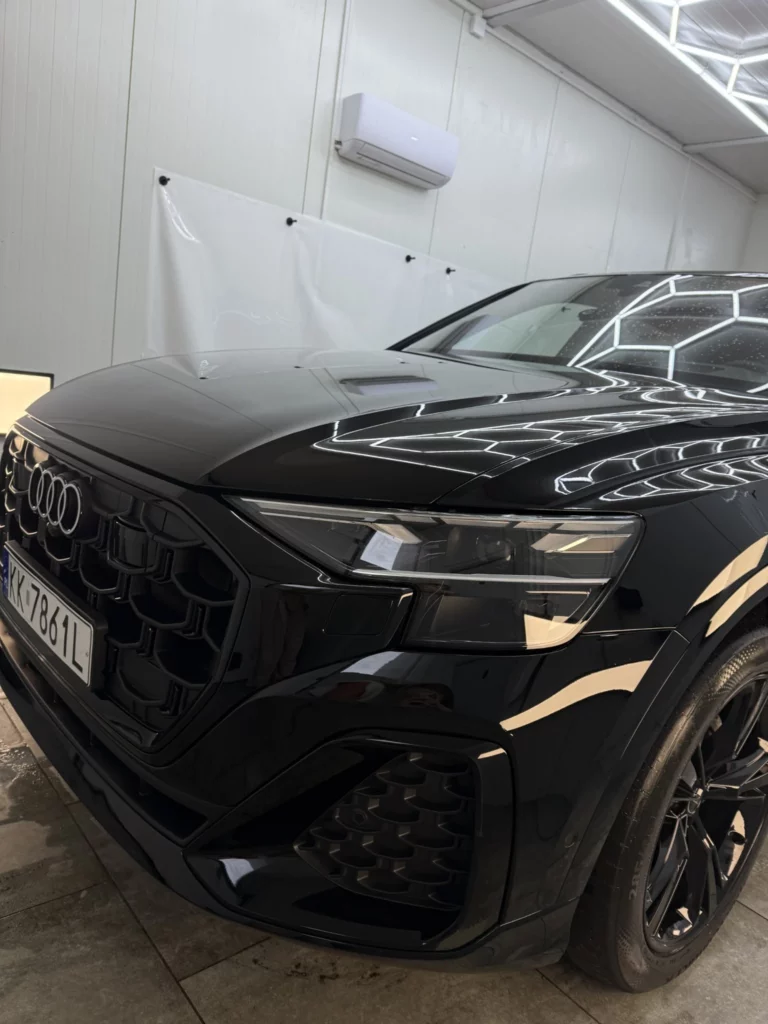 Przód Audi Q8 po oklejeniu na czarny połysk, z widocznym reflektorem i grillem
