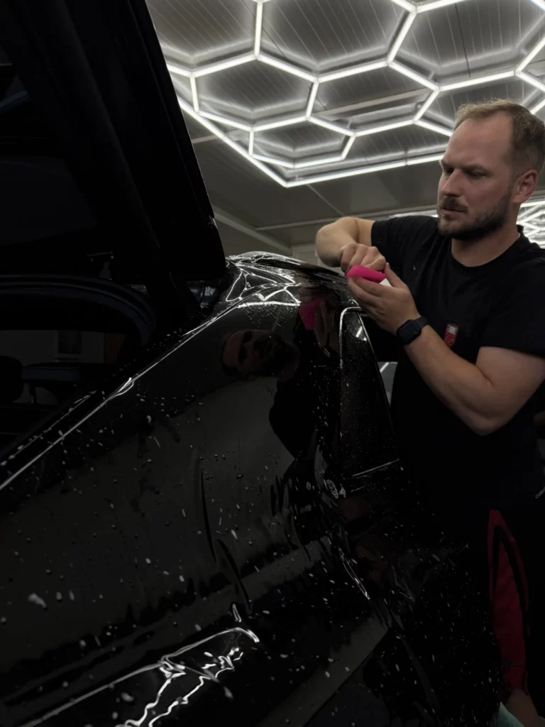 Wygładzanie raklą czarnej folii na bocznym elemencie Audi Q8