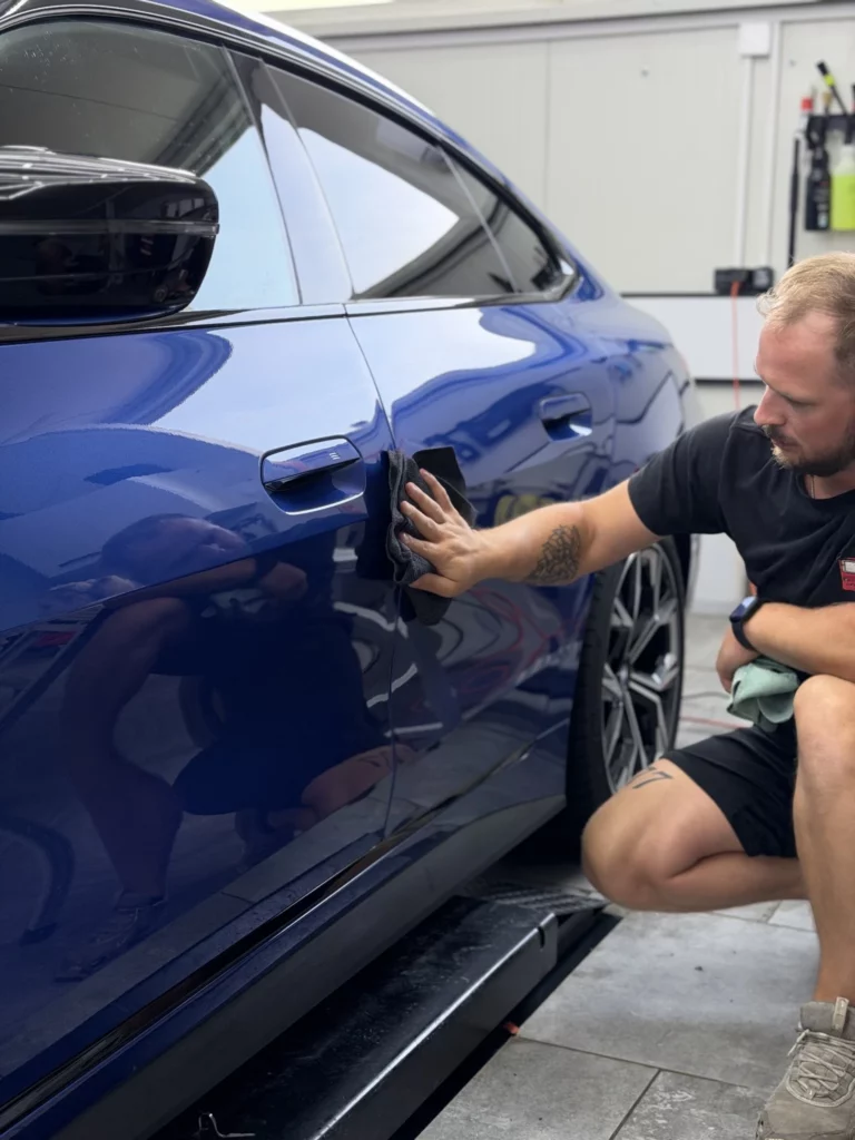 Instalator wygładza folię na bocznych drzwiach BMW serii 4