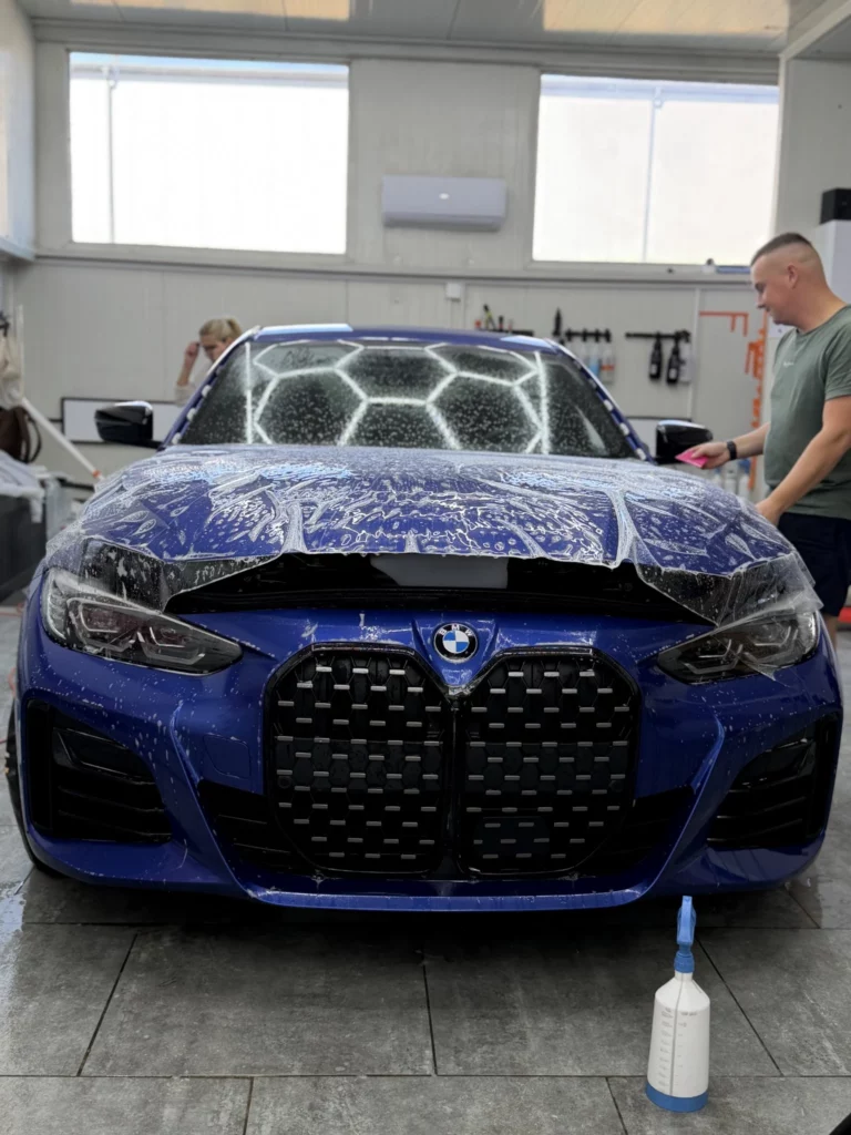 BMW serii 4 od przodu podczas aplikacji folii na masce