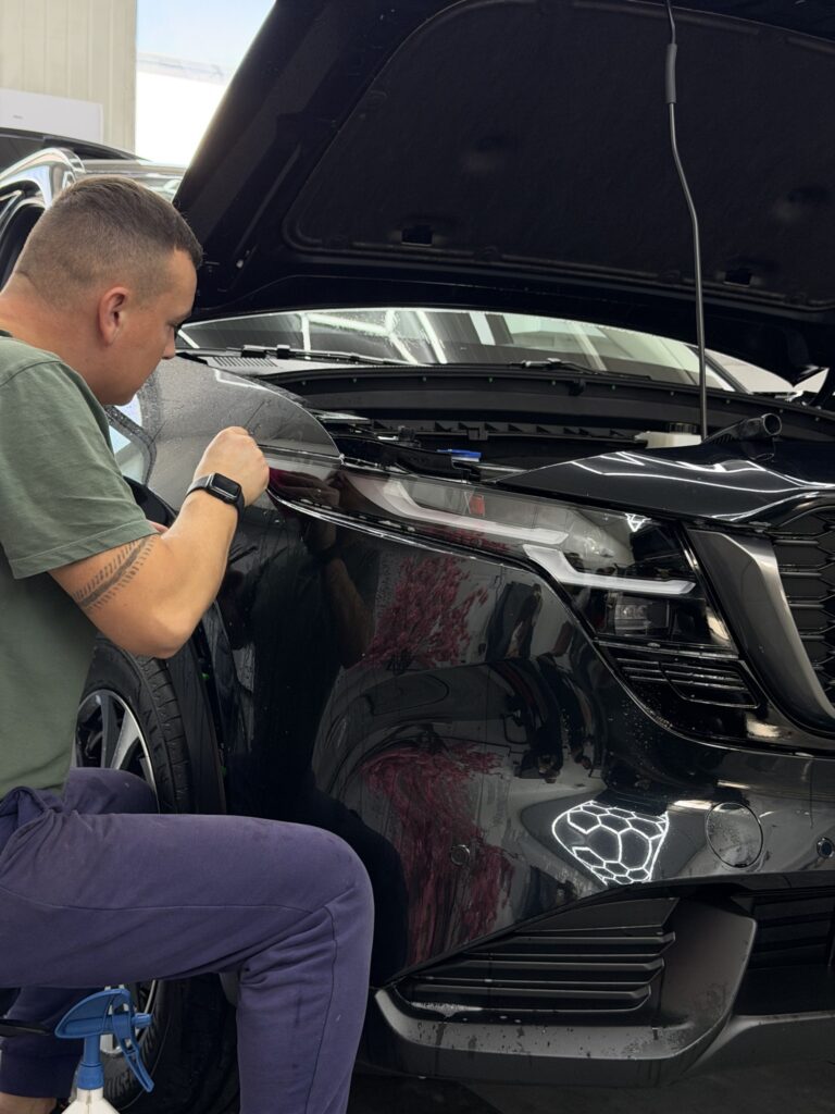 Wykańczanie folii przy przedniej części Mazdy CX-5 z otwartą maską