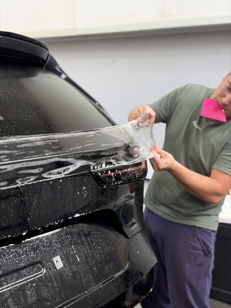 Praca instalatora przy folii na tylnej klapie Mazdy CX-5