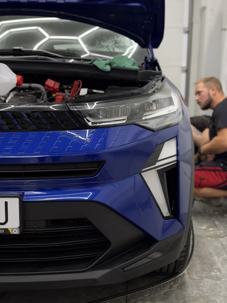 Praca przy przednim zderzaku Renault Captur z otwartą maską