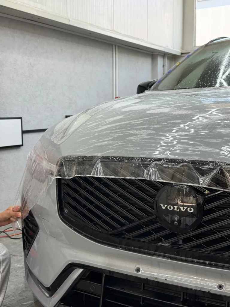 Dopasowywanie folii ochronnej przy krawędzi maski Volvo XC60 nad grillem